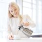 Preview: Junge Dame schenkt Kaffee aus einer Helios Supreme Kanne aus