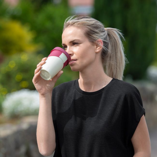 Eine junge Frau trinkt aus einem Waycup-Becher