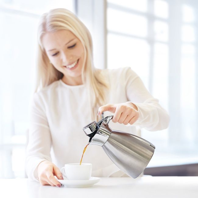 Junge Dame schenkt Kaffee aus einer Helios Supreme Kanne aus